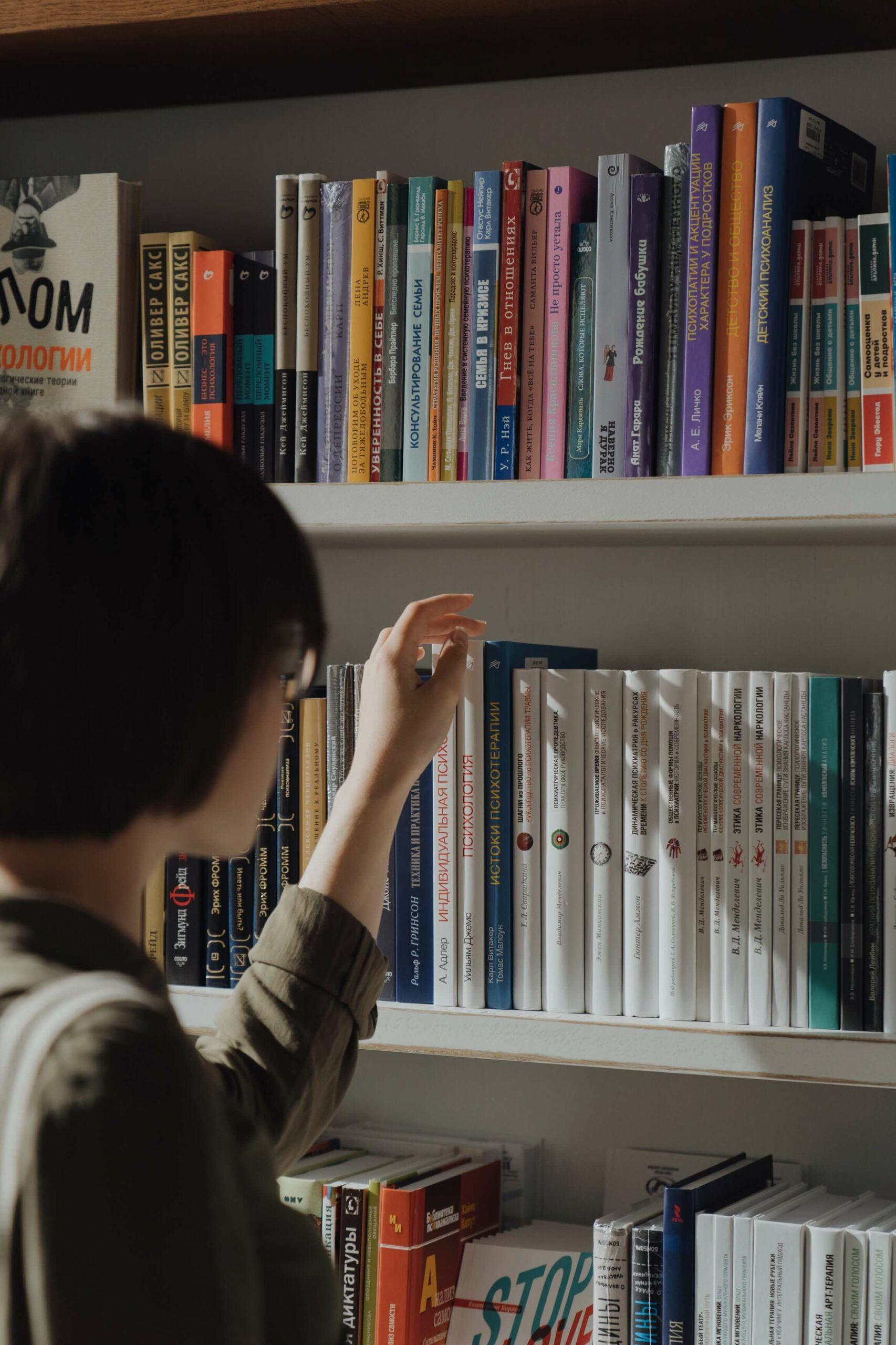 Person choosing a book off of the shelf.
